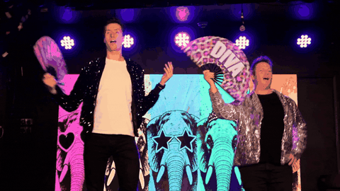 Gossip Queens celebrating on stage with fans and flying confetti.